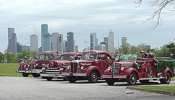 Antique firetrucks with the houston skyline as the background.